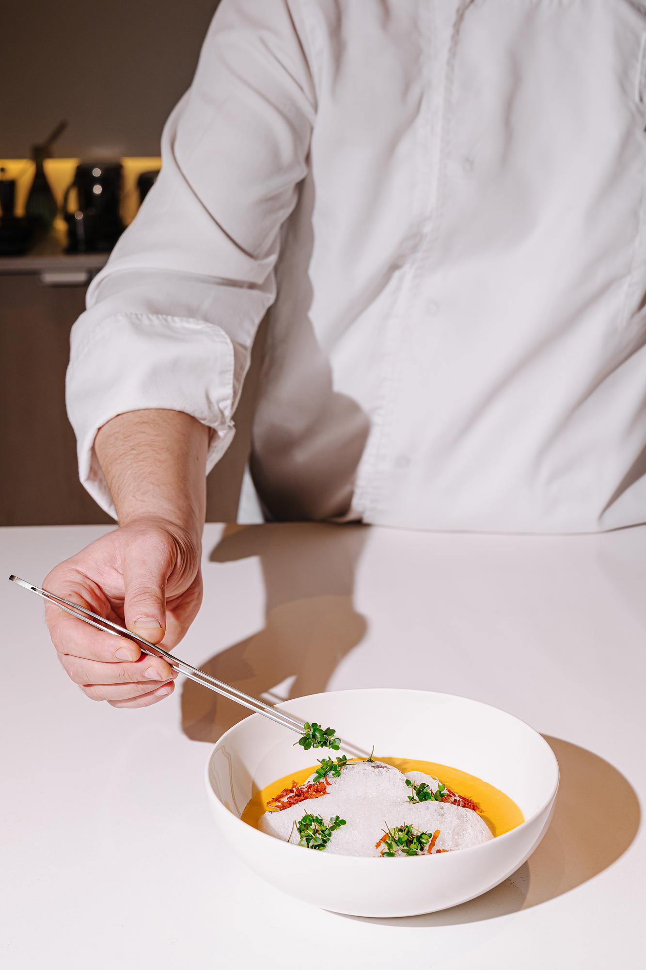Chef arranging a plated course in studio kitchen